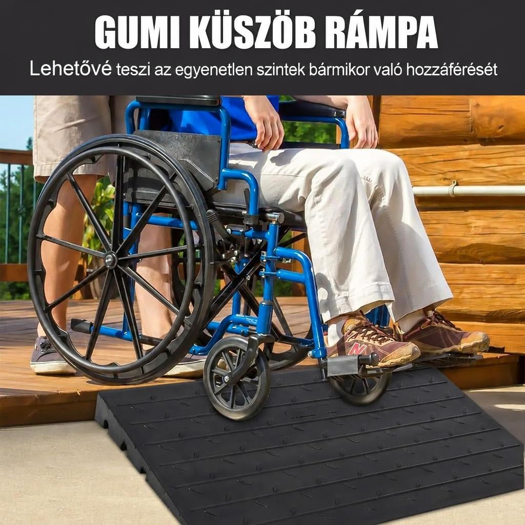 Kerekesszékkel közlekedő személy fekete gumi küszöbrámpán halad át egy fa teraszon.