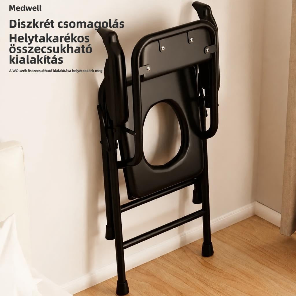 Összecsukott fekete WC-szék a falnak támasztva, helytakarékos tárolást mutatva.