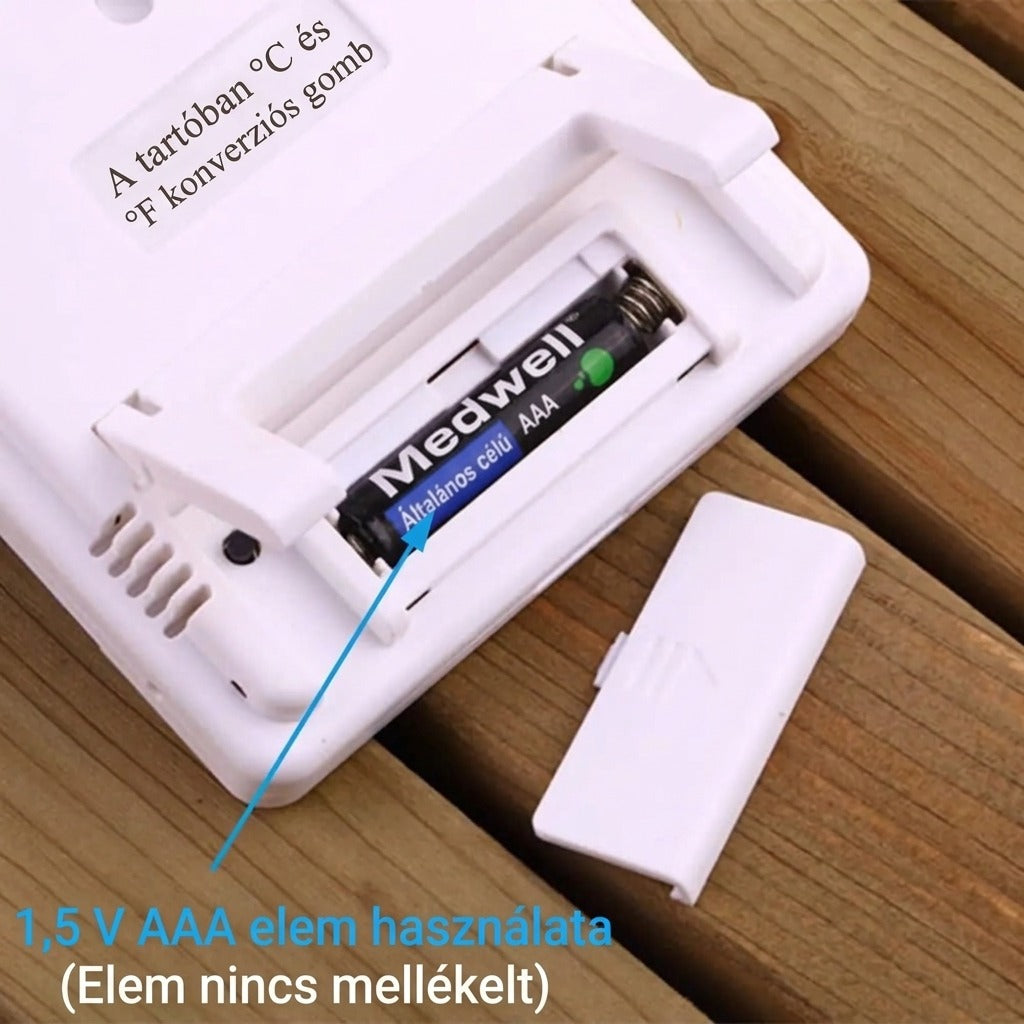 Hőmérő nyitott elemtartóval és egy behelyezett AAA elemmel fa felületen.