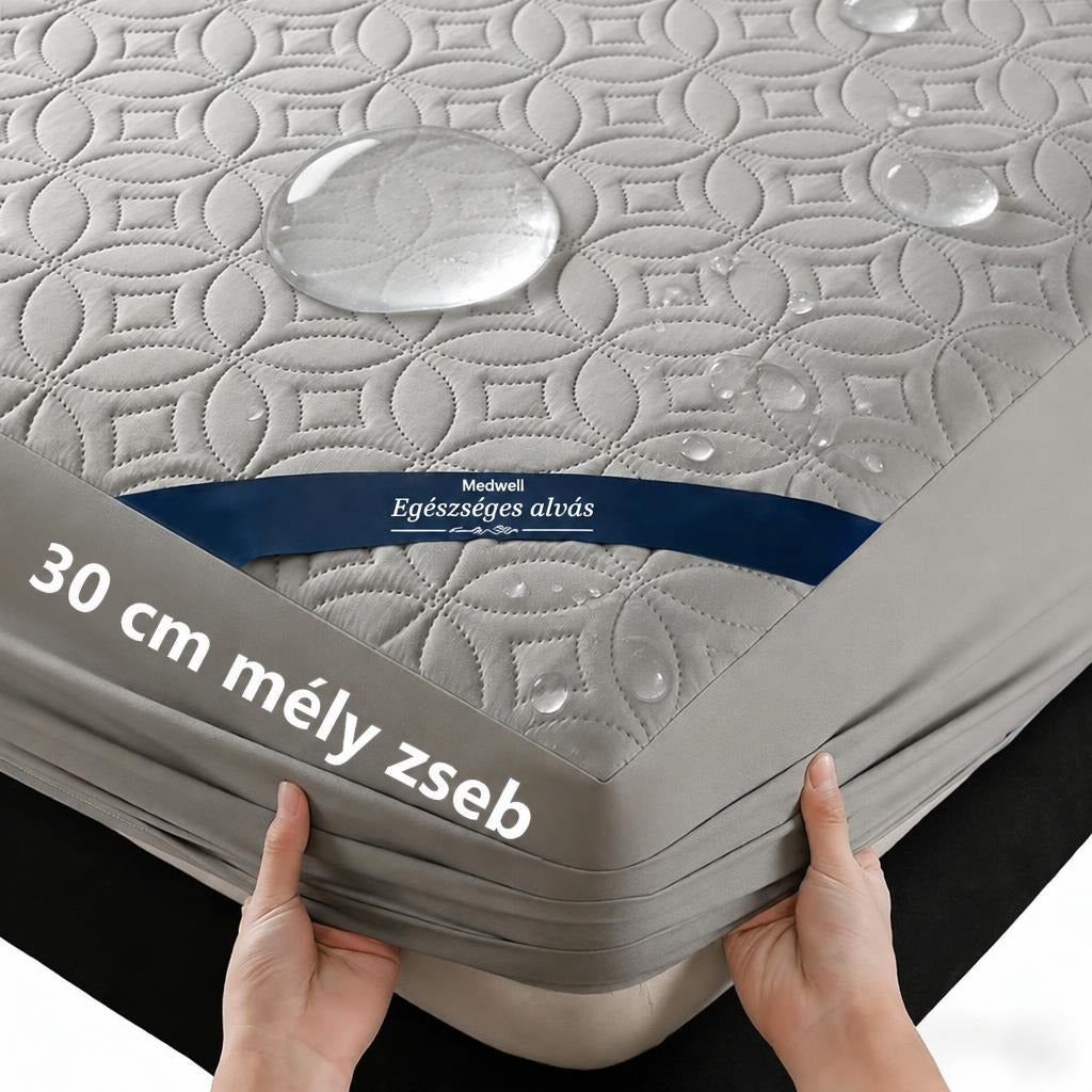 Vízálló, steppelt szürke matracvédő 30 cm mély gumis zsebbel a matracra húzva.